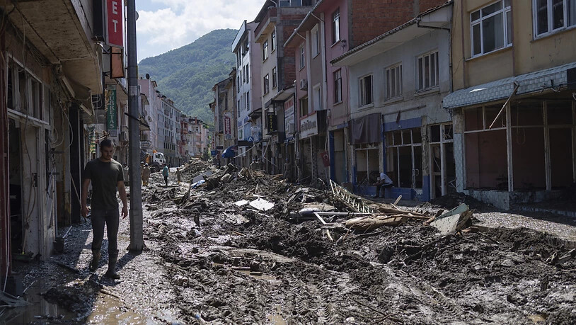 Ein Mann geht durch eine Straße, die voller Schlamm und Schutt ist. In der türkischen Schwarzmeerregion führten heftige Regenfälle in den vergangenen Tagen zu den schlimmsten Überflutungen seit Jahren. Foto: -/AP/dpa