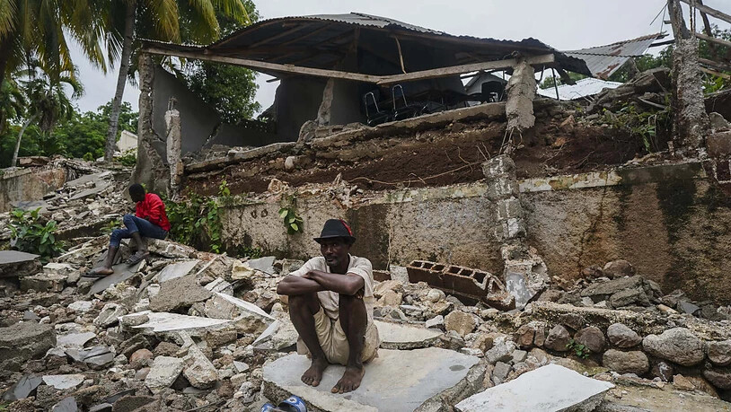 Ein Mann hockt auf den Trümmern des durch das Erdbeben zerstörten Krankenhauses in Fleurant. Die vorläufige Zahl der Erdbeben-Todesopfer in Haiti ist noch einmal deutlich gestiegen. Die haitianische Zivilschutzbehörde meldete am Dienstag via Twitter 1941…