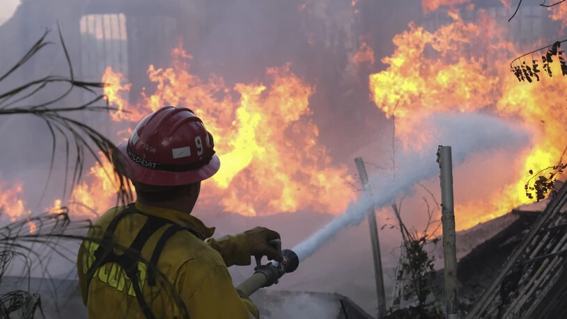 Ein Feuerwehrmann versucht, die Flammen an einem brennenden Haus in Lytle Creek zu löschen, während das «South Fire» brennt. Foto: Ringo H.W. Chiu/AP/dpa