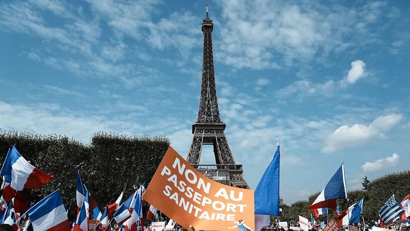 Ein Demonstrant hält während einer Demonstration gegen den Gesundheitspass vor dem Eiffelturm ein Plakat mit der Aufschrift «Nein zum Gesundheitspass» («Non Au Passeport Sanitaire»). Foto: Thibault Camus/AP/dpa