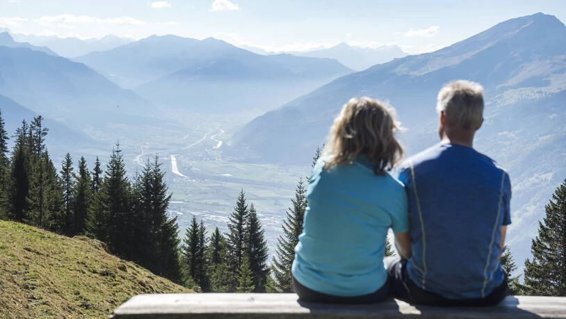 Zwei Menschen geniessen die Aussicht vom Malanser Älpli auf das Bündner Rheintal.
