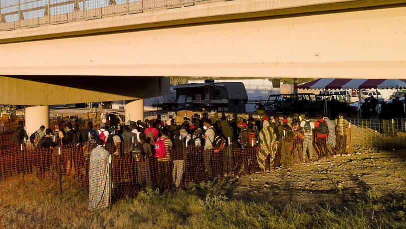 Migranten, viele von ihnen aus Haiti, warten in Schlangen auf Busse unter der Del Rio International Bridge in Del Rio, Texas. Foto: Julio Cortez/AP/dpa