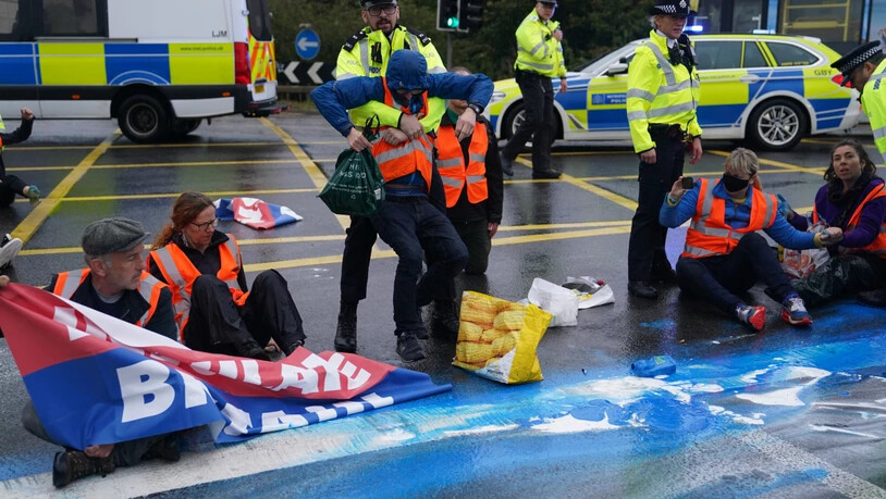 Polizisten nehmen Aktivisten der Organisation «Insulate Britain» auf einer Londoner Autobahn fest. Foto: Steve Parsons/PA Wire/dpa