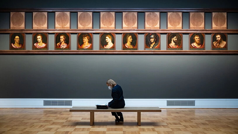 Eine Frau sitzt während eines Pressetermins in der Staatsgalerie Stuttgart in der Sonderausstellung "Becoming Famous. Peter Paul Rubens» vor Ölgemälden auf Eichenholz von Peter Paul Rubens und Werkstatt vor 1600, die römische Imperatoren zeigen. In der…