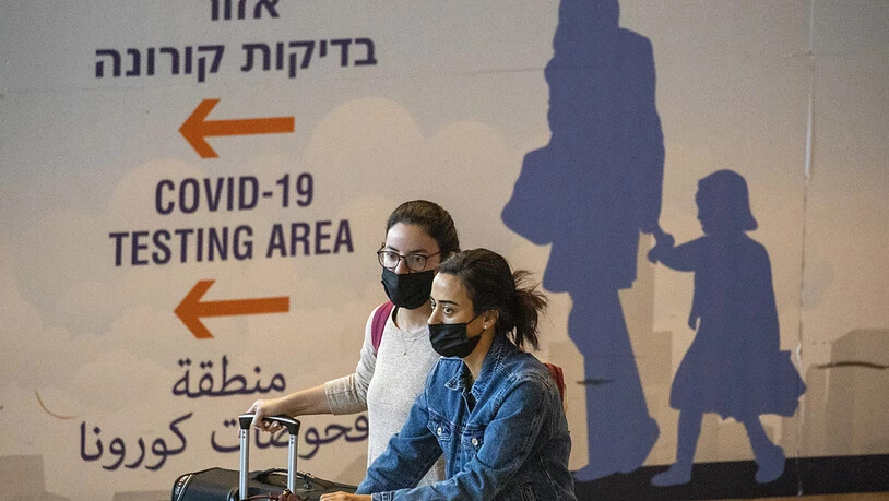 Reisende sind am Ben-Gurion-Flughafen in Tel Aviv unterwegs. Um die Verbreitung der neuen Omikron-Variante des Coronavirus einzudämmen, führt Israel die umstrittene Handy-Überwachung von Corona-Patienten und deren Kontakten wieder ein. Foto: Ariel…