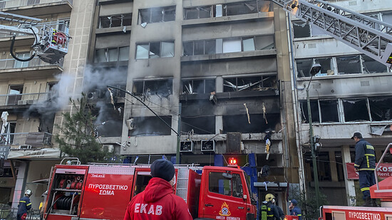 Feuerwehrleute suchen mit Hilfe von Drehleitern nach Personen, die nach der Explosion im Herzen Athens möglicherweise in den beschädigten Gebäuden eingeschlossen sind. Foto: Derek Gatopoulos/AP/dpa
