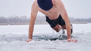 Eisbaden extrem: Ein Mann steigt bei Minusgraden mit einer Mütze ins Wasser.